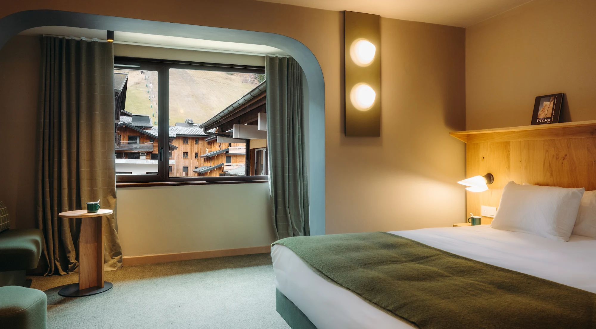 Chambre avec alcôve vitrée donnant sur les chalets et la piste de ski, appliques murales rondes, Chambre Cosy