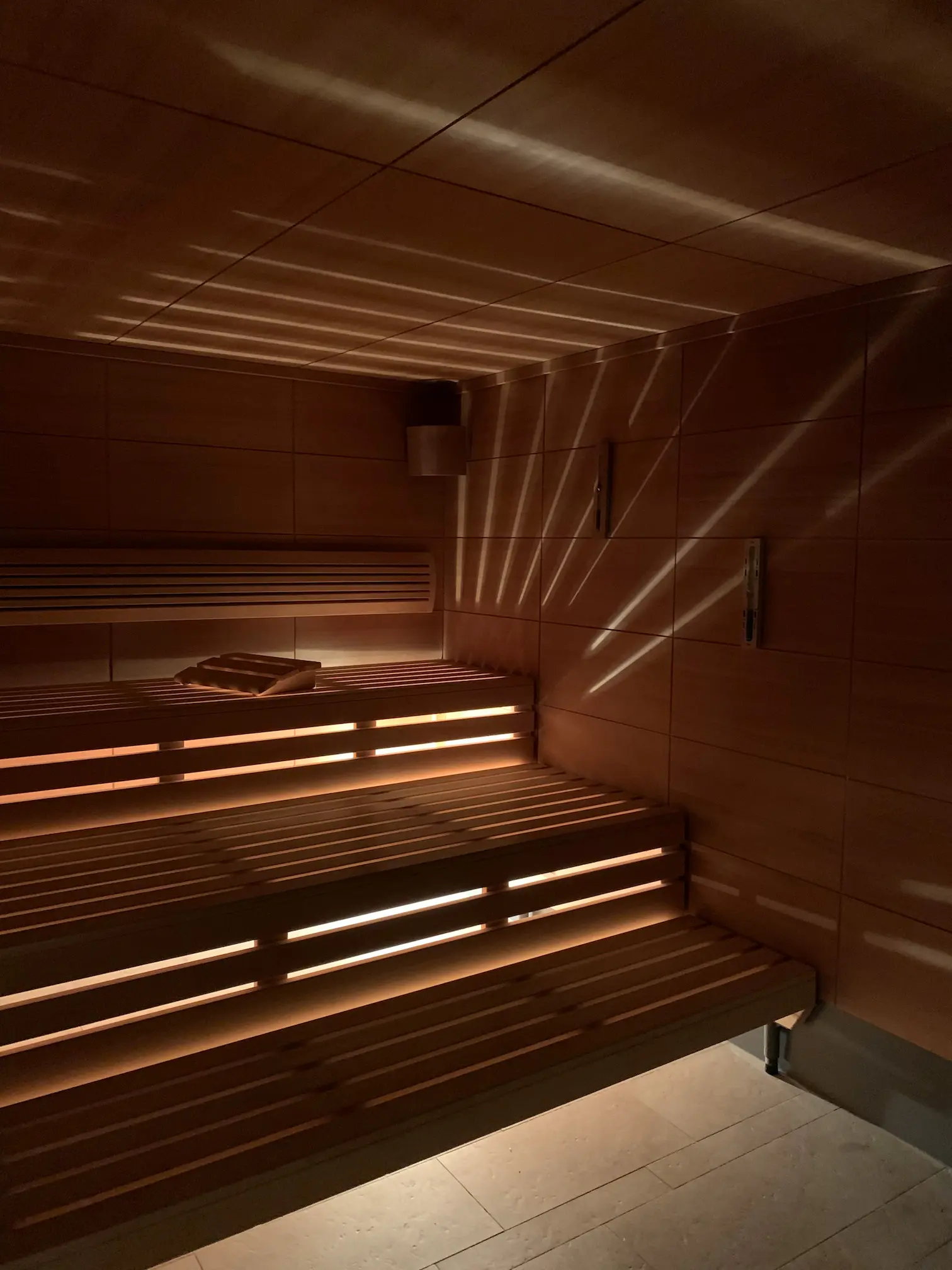 Intérieur d'un hammam en bois avec bancs éclairés et jeux de lumière