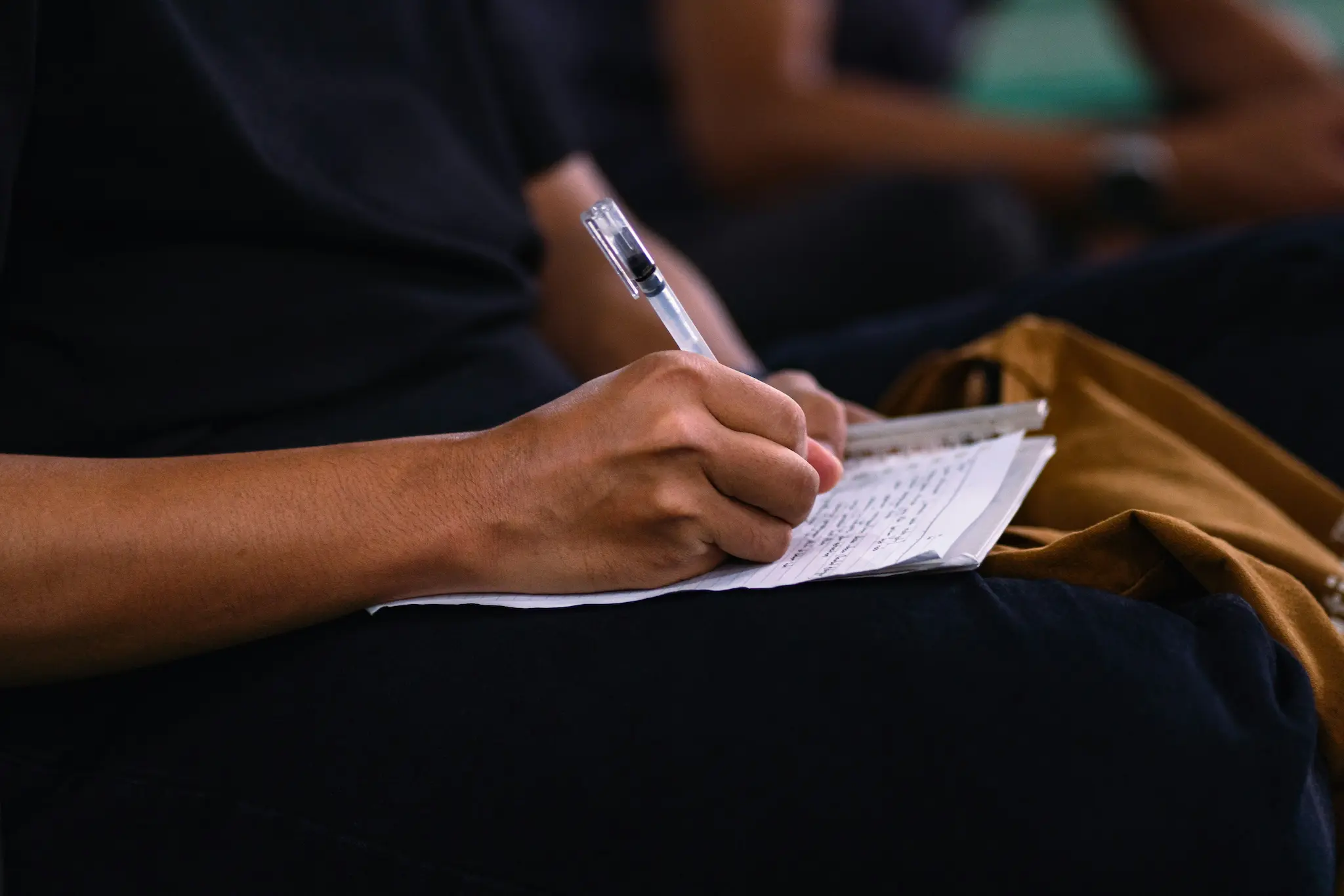 Main prenant des notes au stylo dans un carnet pendant un séminaire