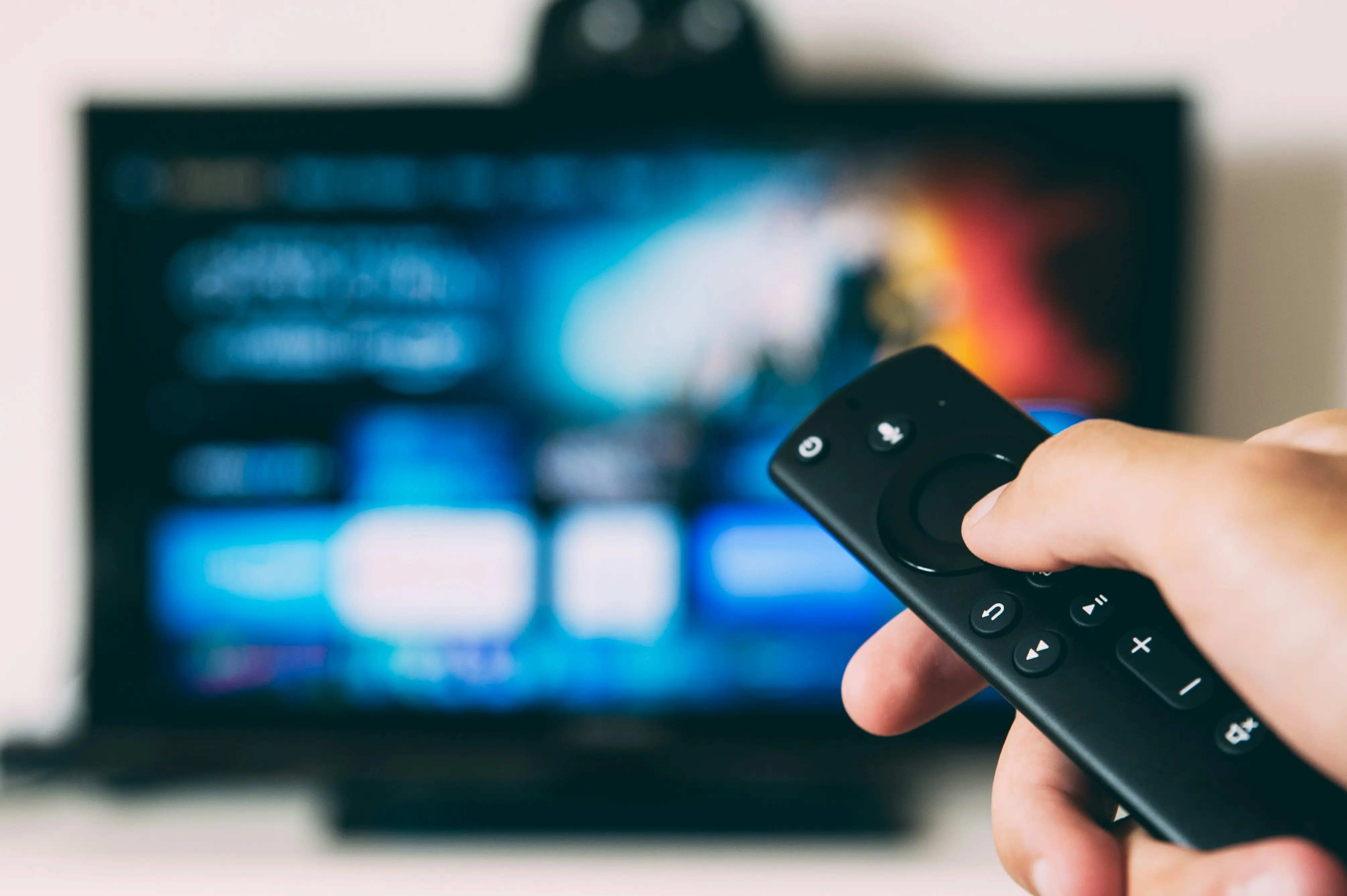 Main tenant une télécommande dirigée vers un téléviseur affichant une interface de streaming