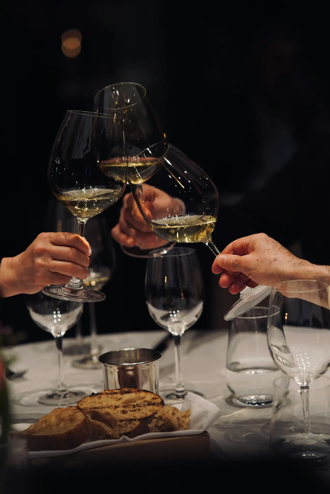Two glasses of white wine clinked together during a candlelit dinner