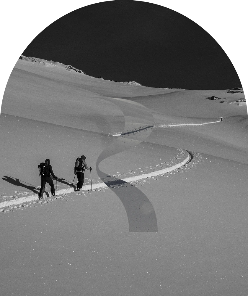 Deux randonneurs à ski progressant sur une pente enneigée, photo en noir et blanc