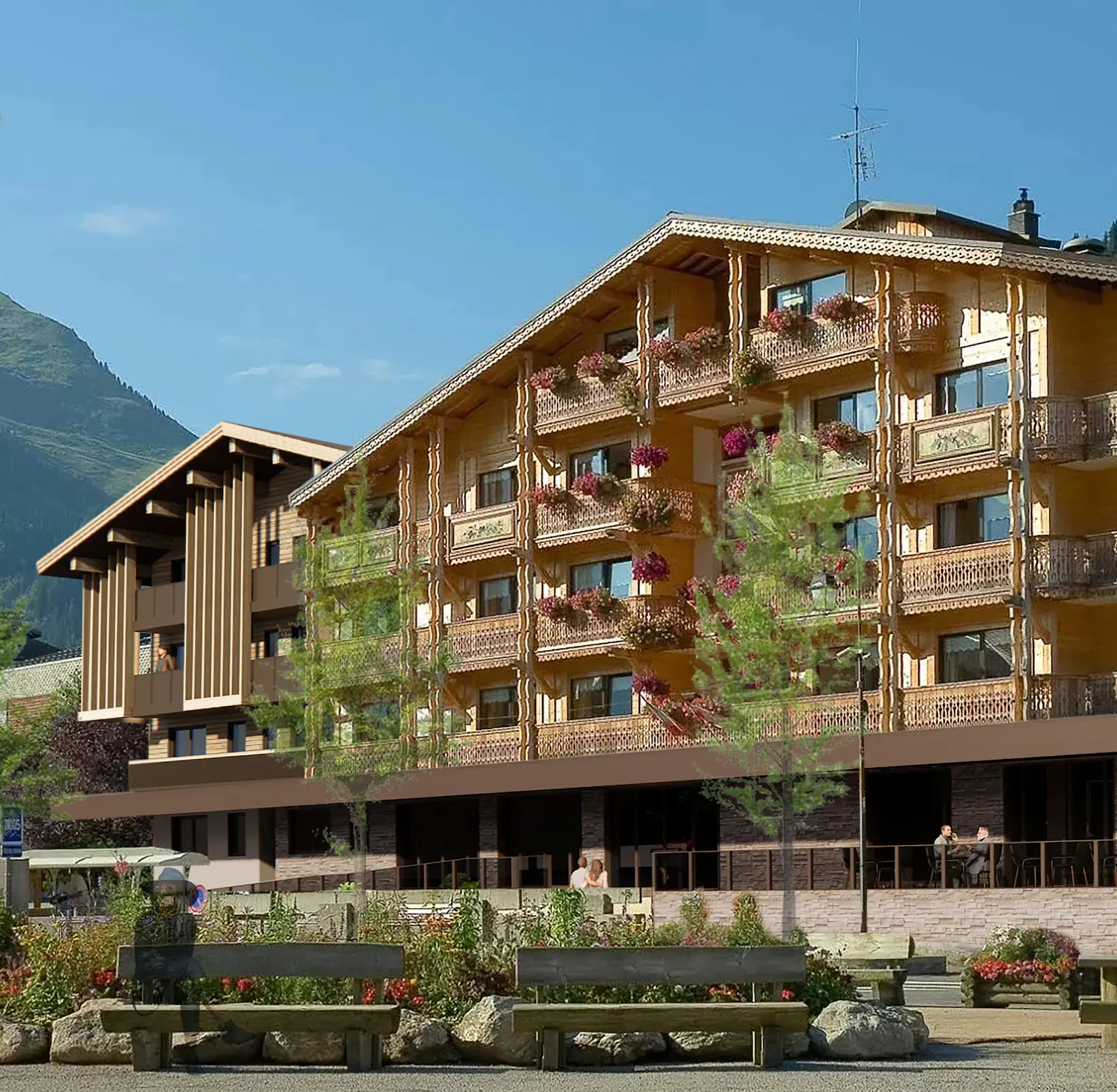 Façade en bois de la résidence Les Airelles avec balcons fleuris et terrasse, montagne en arrière-plan