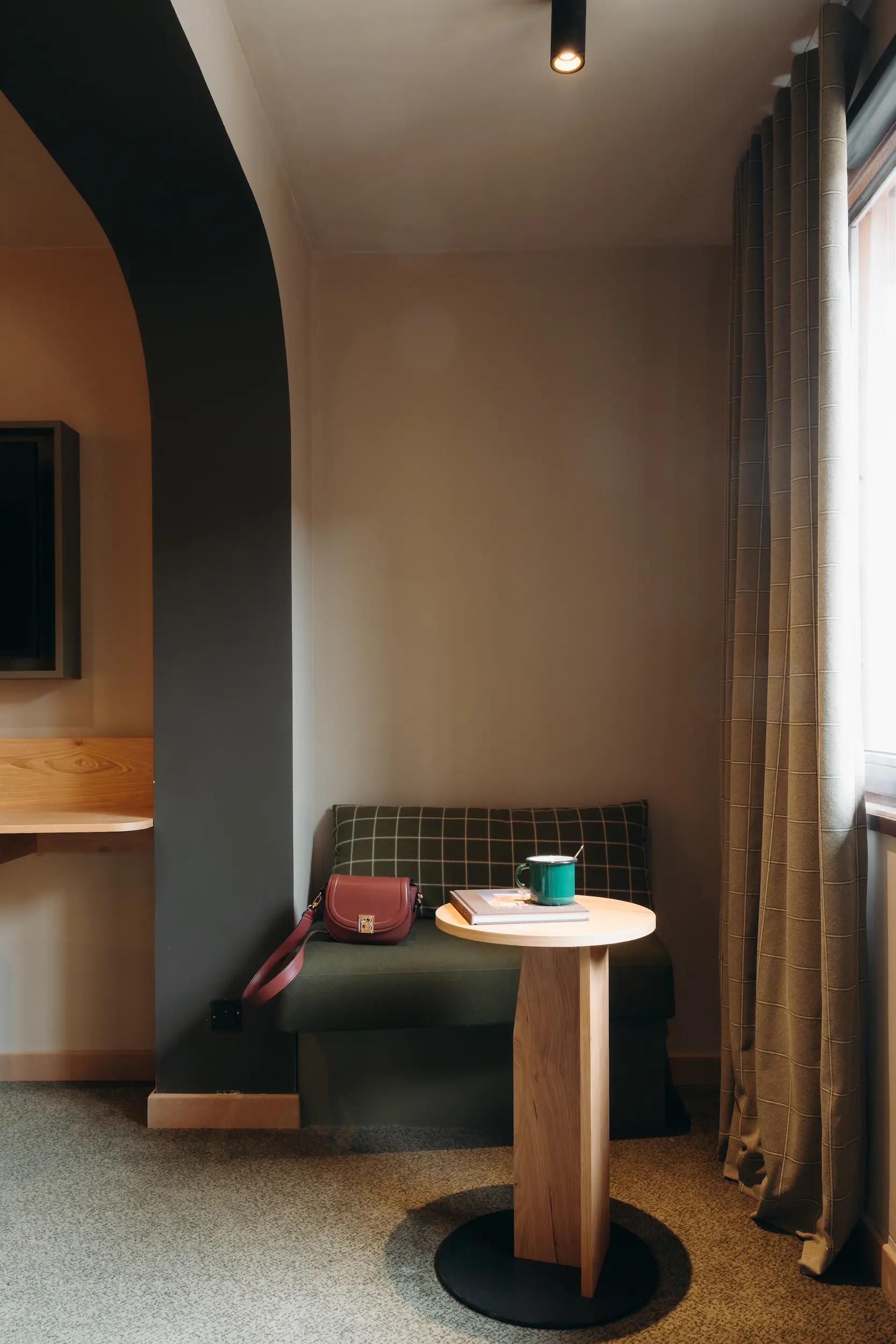 Alcôve voûtée sombre avec banquette, table ronde et rideau à motifs, Suite Montagne