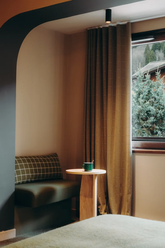 Banquette dans une alcôve avec table ronde en bois et vue sur les sapins, Suite Garance