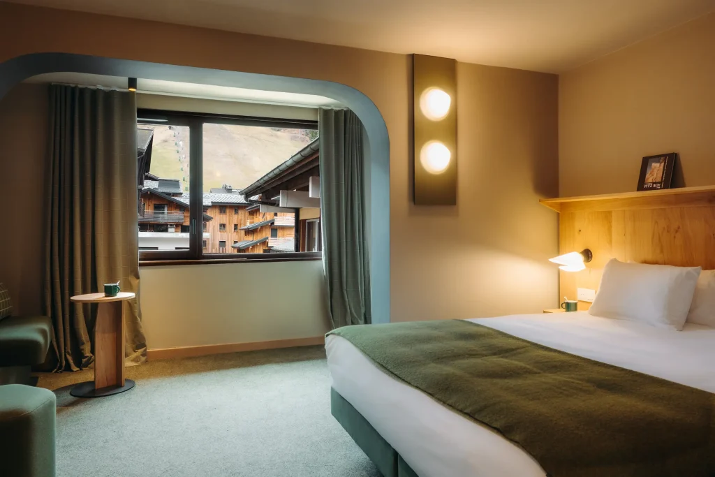 Chambre avec lit à tête de lit en bois, appliques murales rondes et vue sur la montagne depuis l'alcôve, Suite Montagne